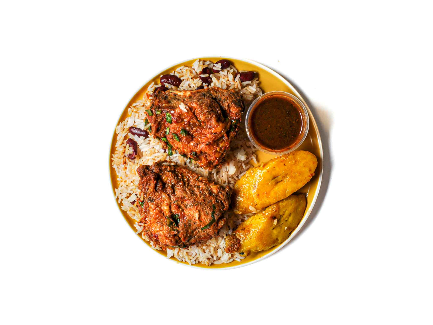 Peaches Patties' Ginger Tamarind Chicken features tender chicken infused with bold ginger and tangy tamarind, served alongside crispy fried plantains and fragrant jasmine rice. This dish offers a delightful fusion of sweet, tangy, and savory flavors for a truly satisfying meal.