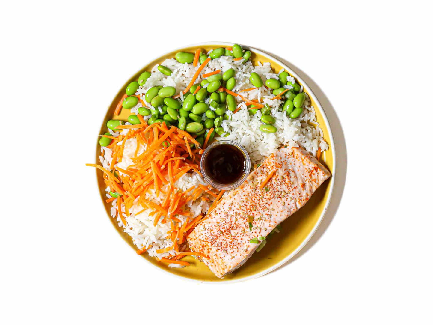 Buddha Bowl's Teriyaki Glazed Salmon features tender, perfectly cooked salmon fillets brushed with a rich and savory teriyaki glaze. This is paired with white rice and steamed edamame beans. This dish offers a delightful balance of sweet and savory flavors, creating a delicious and satisfying meal.