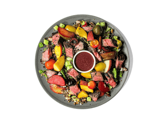 Juicy skirt steak, marinated in dark balsamic and fresh herbs, is grilled to perfection and served over a vibrant quinoa pilaf tossed with yellow-eyed beans, gorgonzola, and toasted walnuts. Sweet peaches, nectarines, plums, cherries, crisp cucumbers, and heirloom tomatoes add fresh bursts of summer flavor, while a cherry balsamic vinaigrette ties it all together. High in protein and antioxidants, this colorful dish nourishes body and palate alike.