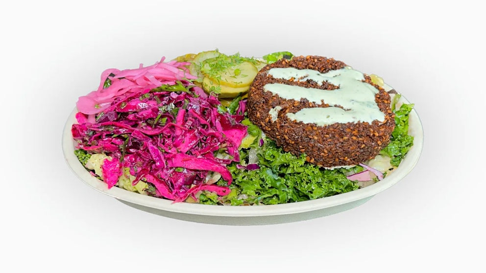 NomNom Burger's Protein Style Falafel Burger features a crispy falafel patty served without the bun, wrapped in fresh lettuce. Topped with tangy pickled onions and melted American cheese, this low-carb option offers a delicious mix of savory flavors and crunchy textures.