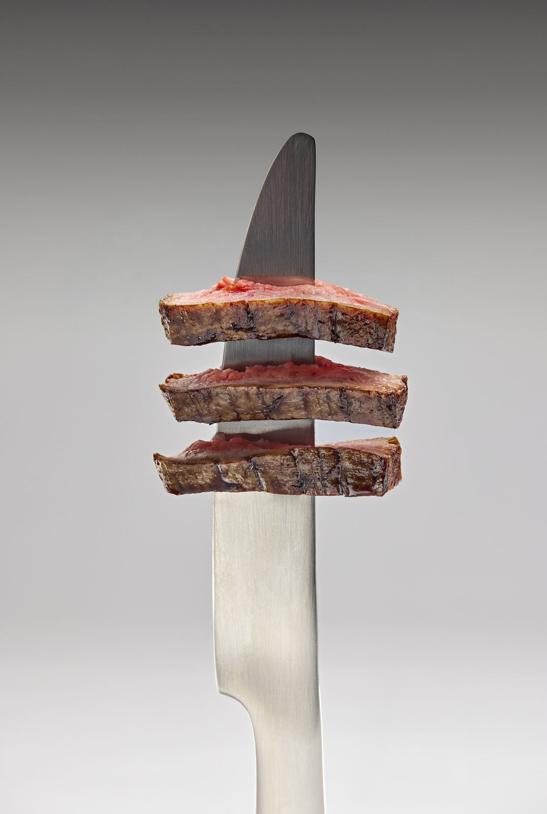 Grass-fed steak slices on a knife